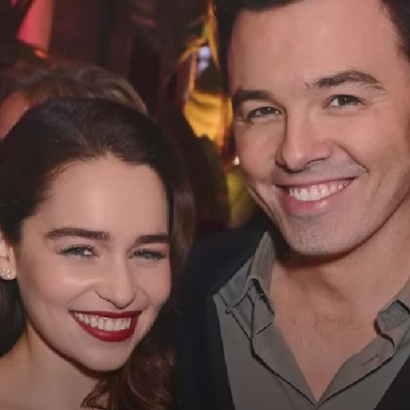 Emilia Clarke and Seth MacFarlane are side hugging each other as they are smiling for the camera.